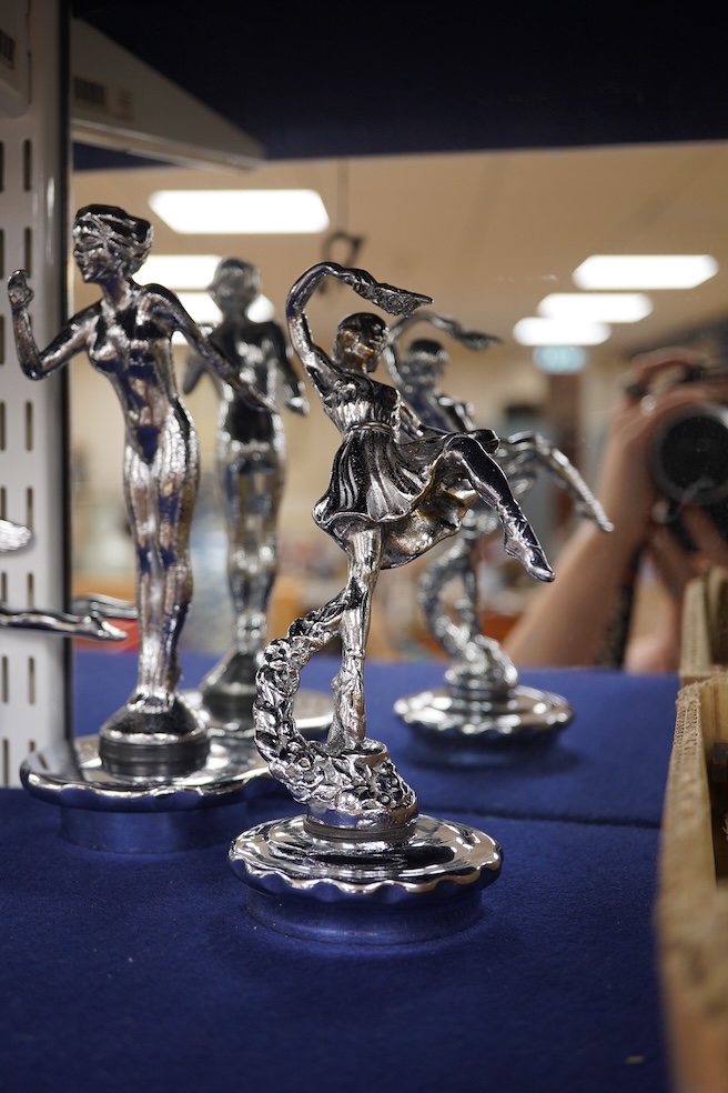 Five chrome car mascots in the form of female dancing figures, three mounted on threaded radiator caps, one with a registration number: 675619, one a stylised Art Deco winged female figure astride a globe. Condition - fa